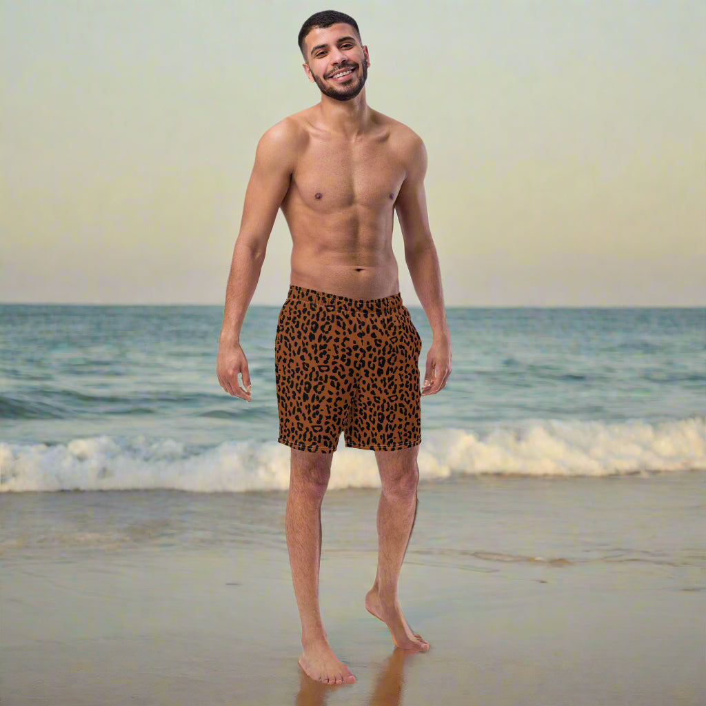 man wearing a brown and black cheetah print swim trunks at a beach.