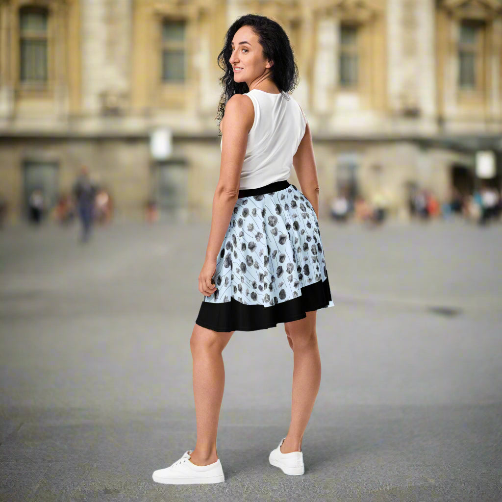 woman wearing a light blue skirt with black and grey poppies on it.