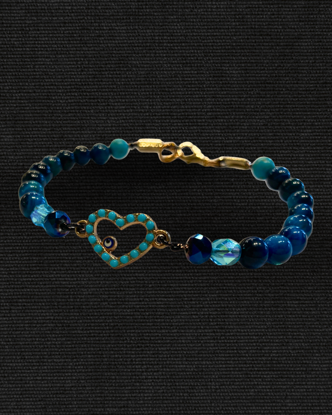 evil eye Bracelet with blue beads and a heart-shaped clasp on a black background