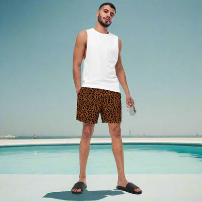 man standing in front of a pool with a dark brown and black cheetah print bathing suit. 
