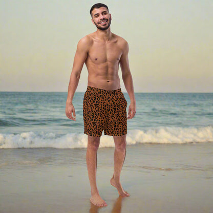 man wearing a brown and black cheetah print swim trunks at a beach.